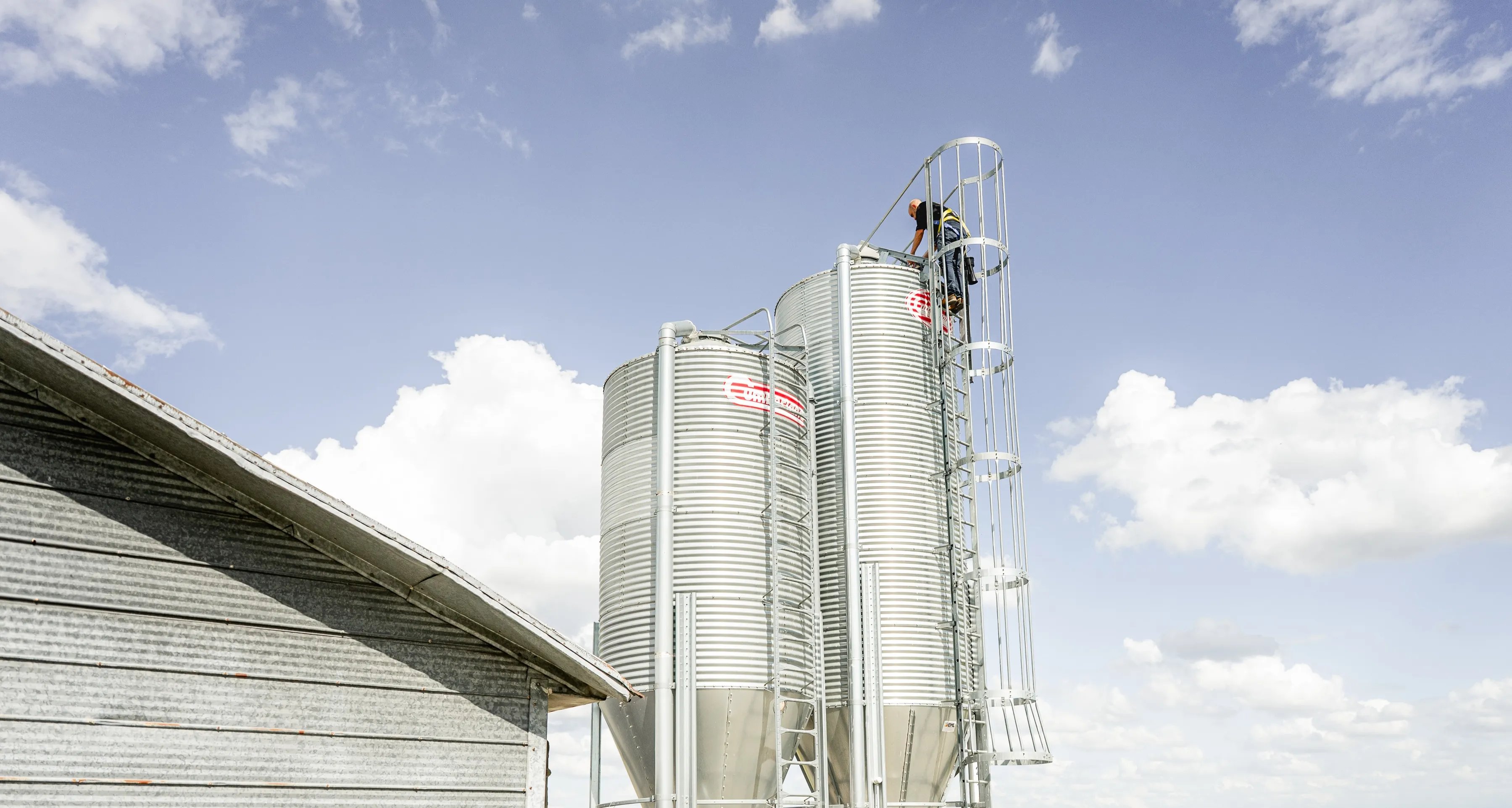 Un opérateur inspecte le sommet d'un silo à grain sous un ciel dégagé